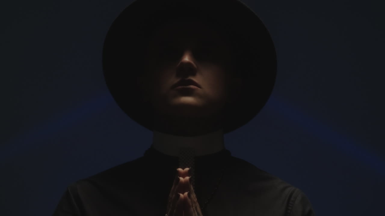 Praying Man in Priest Costume Posing in Dark Studio