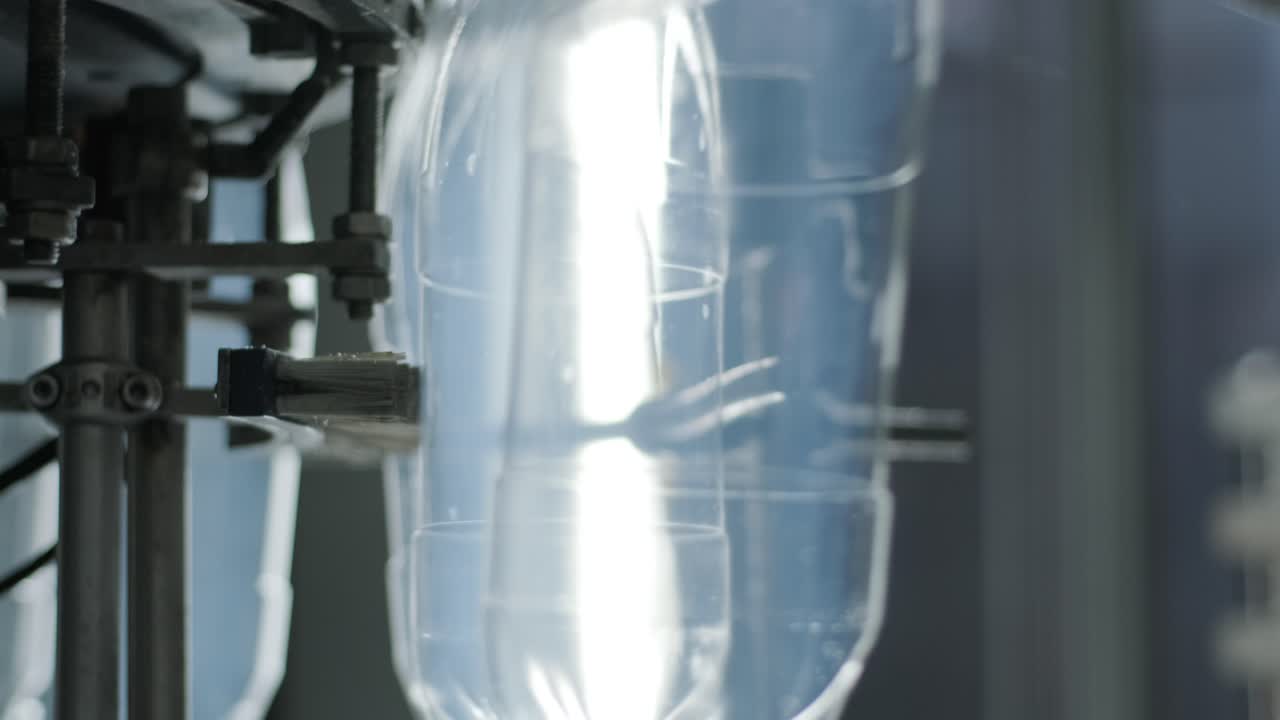 Automatic filling machine pours water into plastic PET bottles at modern beverage plant