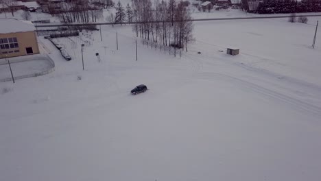 SUV-Negro-Conduce-Alrededor-Del-Campo-De-Nieve-Con-Rollo,-Haciendo-Pista-Para-Esquiar