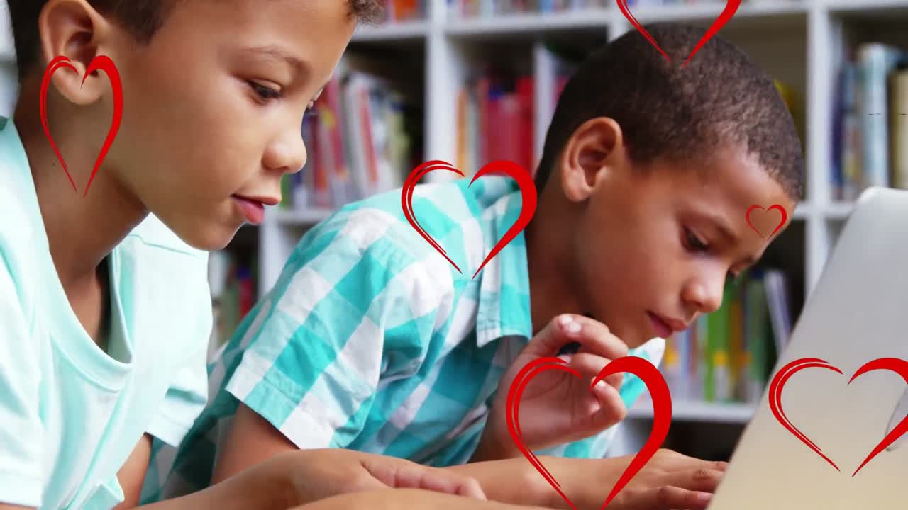 múltiples iconos de corazón rojo flotando sobre dos niños diferentes usando una computadora portátil en la escuela