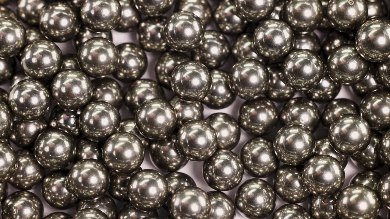 Close-up video of numerous ball bearings colliding and settling, showcasing metallic reflections and dynamic movement