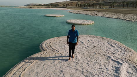 hombre adulto caminando descalzo sobre la formación de sal en el mar muerto durante el día en israel