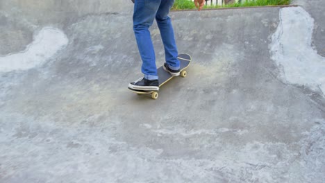 Sección-Baja-De-Un-Joven-Practicando-Trucos-De-Skate-En-Rampa-En-El-Parque-De-Skate-4k