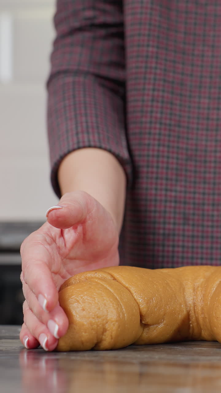 손을 꺼내서 반죽을 는 것을 끝내는 여성의 하부 몸의 모습, 뜨거운 조명과 현대적인 부 장비를 특징으로하는 흐릿한 배경으로 부 카운터에 모양의 반죽을 남기고