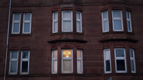 three panel windows of kitchen living space on side of dark building facade, static