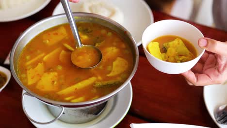 ladling soup into a bowl at a table