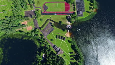 topdown view sports complex in waterfront lush grass field, drone descending shot