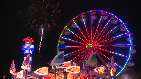 fireworks explode in the night sky behind a ferris wheel at a carnival or state fair 2