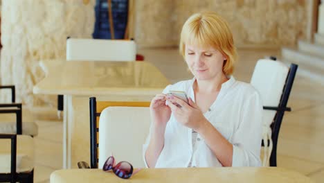 Eine-Frau-In-Sommerkleidung-Ruht-In-Einem-Café-Mit-Einem-Telefon-Im-Urlaub-In-Verbindung-Mit-Der