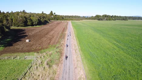 following a group of cyclists as they ride along a straight gravel road, old coach road, ohakune, new zealand