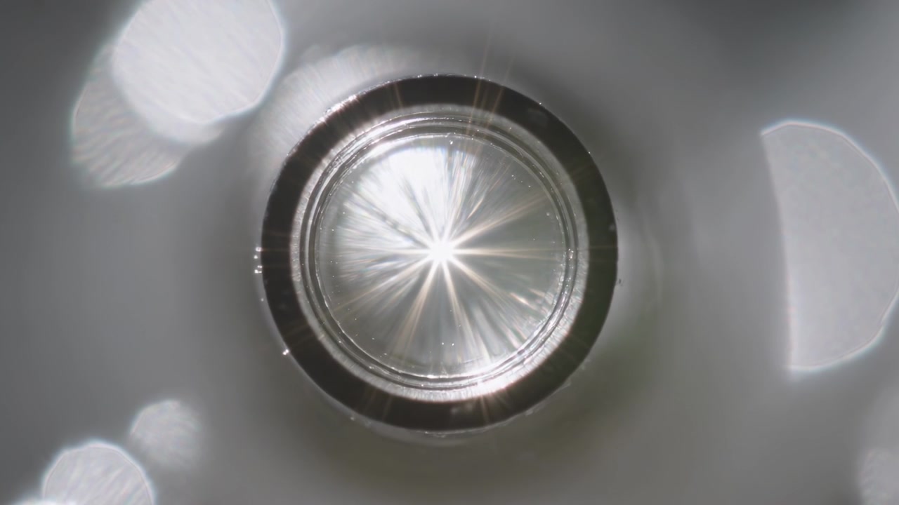 Mostrando un riflettore a raggiera che reagisce ai cambiamenti di luce in un tubo, con segni ad anello e bokeh esagonale.