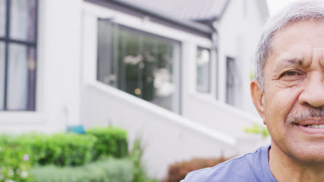 Portrait-of-happy-senior-biracial-man-looking-at-camera-in-garden