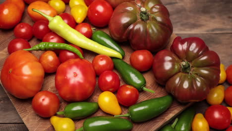 endecha plana sobre madera de palet rústica envejecida tomate morado cherokee pimiento jalapeño tomates rojos y amarillos cayena y pimiento amarillo con tabla de cortar de madera dura