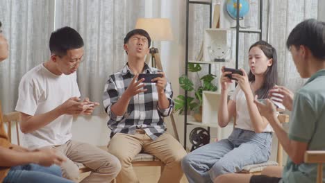 asian teen group sitting in chairs forming a circle playing game on smartphone at home. disappointed loosing game with upset face