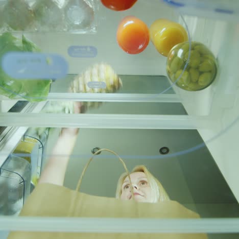 A-Young-Woman-Loads-The-Food-In-The-Fridge