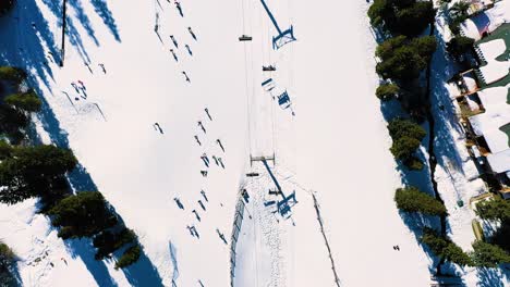 above view of people skiing and riding chairlifts down ski slopes through thick powder snow