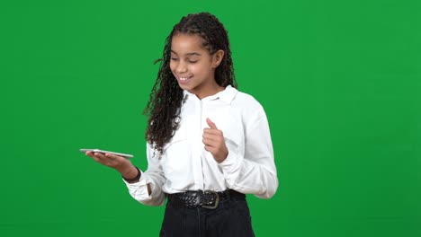 relaxed teen girl tapping finger on smartphone touchscreen smiling on green screen. surprised african american teenager with futuristic modern technology at chromakey background.