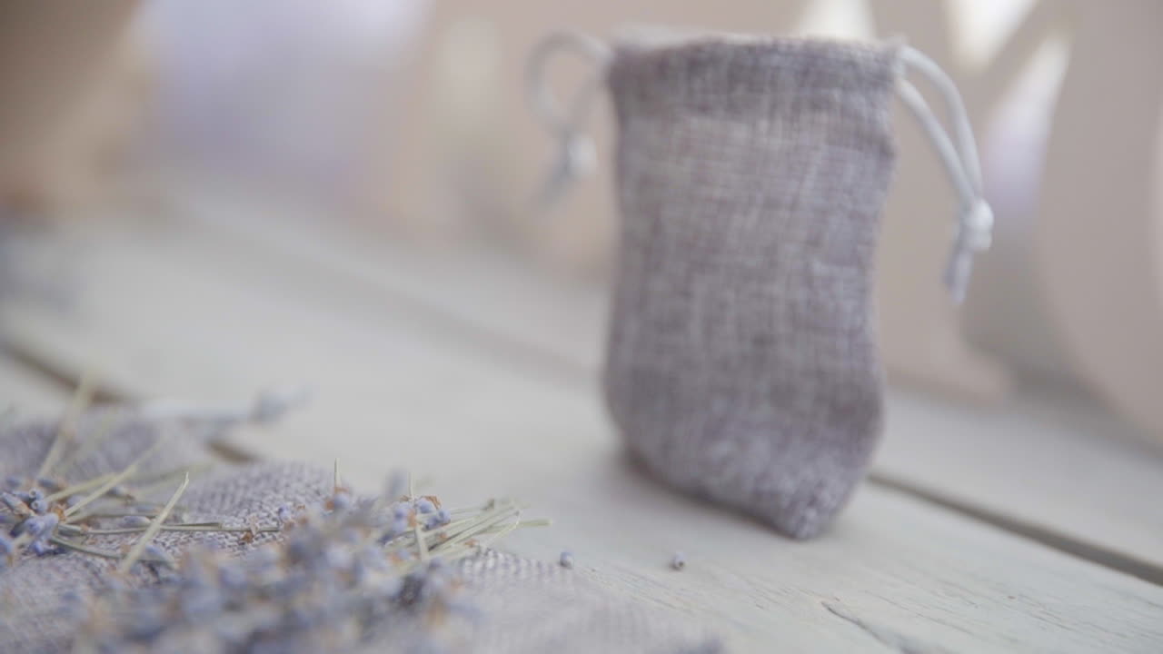 Una mano femminile posa un mazzo di lavanda su un tavolo di legno.