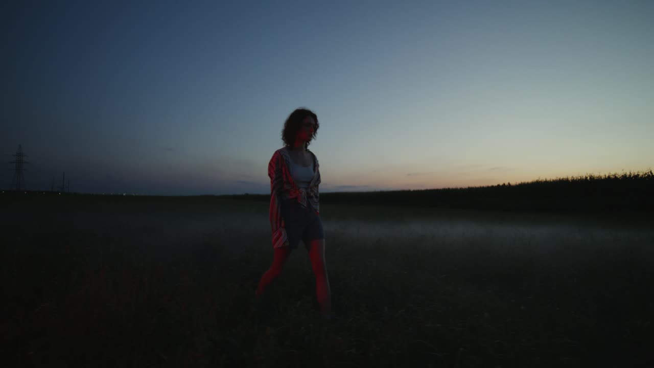 Nainen kävelemässä pellolla auringonlaskussa