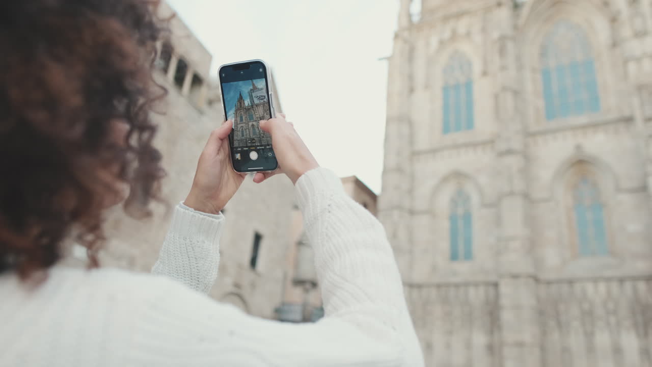 Woman taking photo of cathedral with smartphone