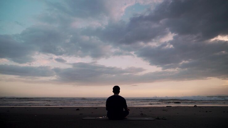 Man Meditating on Beach at Sunset