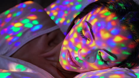 woman sleeping with colorful light patterns on her face