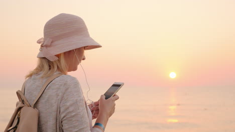 Keine-Minute-Ohne-Telefon-Steht-Das-Mädchen-Am-Strand-Mit-Einem-Rosa-Himmel-Und-Einem-Himmel,-Der-Auf-Sie-Schaut