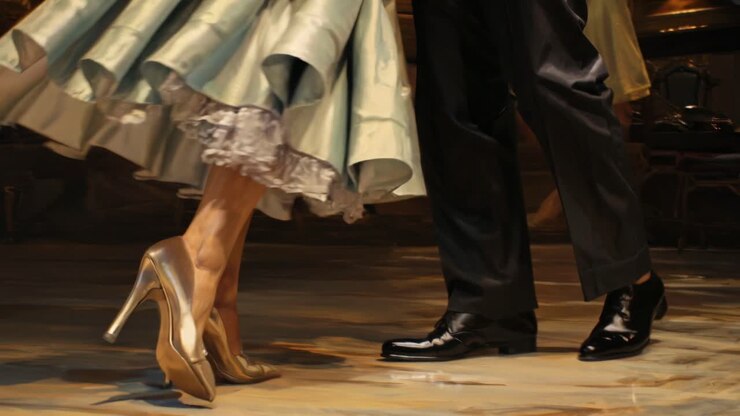 Close-up, low-angle video shot of elegant dancers' feet in motion on a polished floor