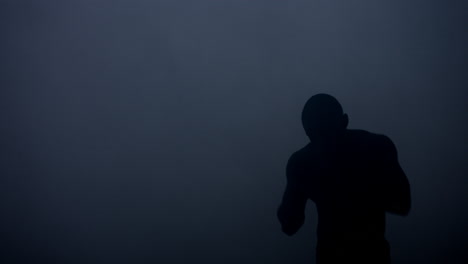 Silueta-De-Boxeador-En-Un-Estudio-Oscuro.-Luchador-De-Mma-Calentando-Antes-De-La-Pelea