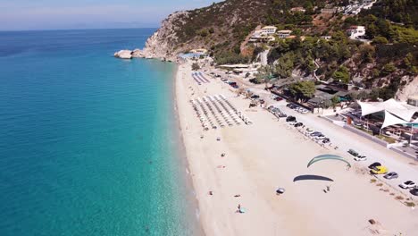 Parapente-Turístico-En-La-Playa-De-Kathisma,-Isla-De-Lefkada,-Grecia---Antena-De-Marcha-Atrás