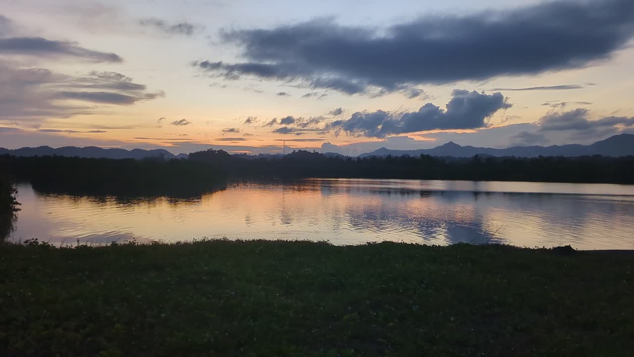 Wide panning shot of panoramic river and scenic clouds during sunset with silhouettes in the Philippines.