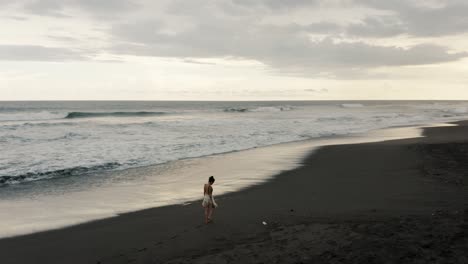 Mujer-Caminando-Por-La-Playa-En-El-Paredón,-Guatemala-Al-Atardecer---Toma-Aérea-De-Drones