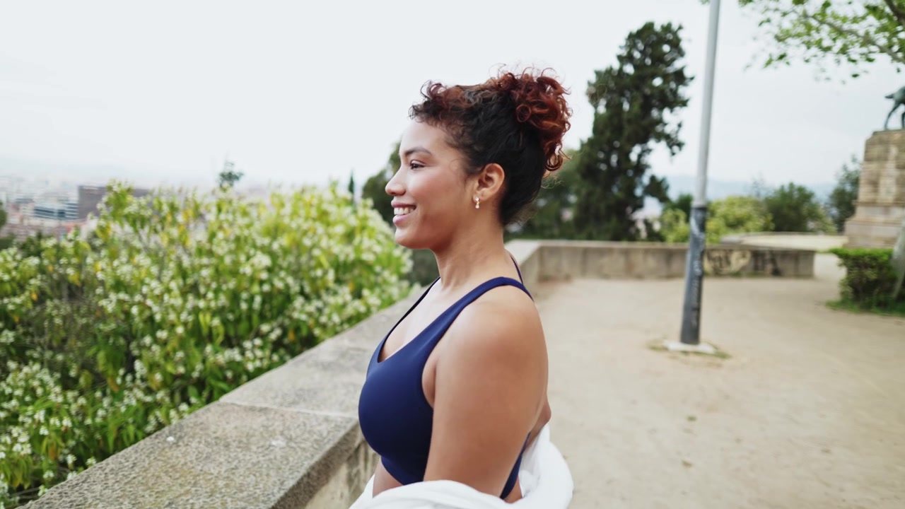 Jovem mulher tirando o casaco e sorrindo em um parque ao ar livre
