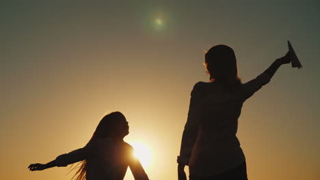 a woman is playing with a daughter a paper airplane the child is running happily alongside happy tim