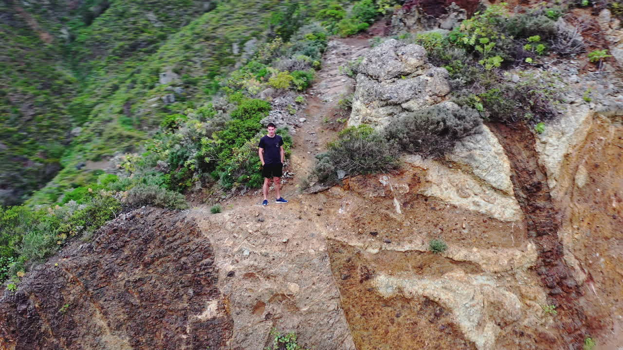guy de pie sobre una roca por encima de una carretera de montaña, tenerife, islas canarias, españa