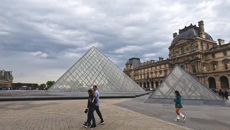 tourists walking around the iconic louvre pyramid