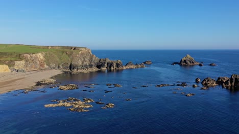 Aerial-view-of-the-Blue-water,-rocky-coastline-including-a-sea-arch-and-beach-in-Waterford-along-the-South-of-Ireland