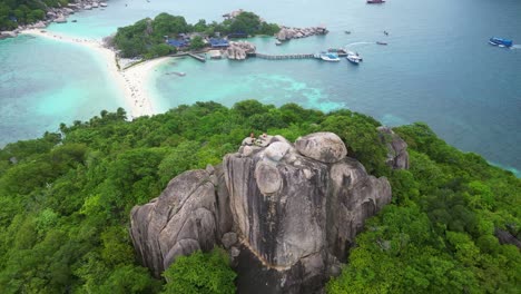 aerial view of a rocky coastline with turquoise waters, green vegetation, and a sandy beach, showcasing a scenic tropical landscape.