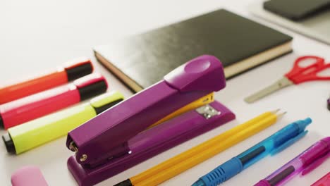 video of diverse colorful pen, notebook, scissors and punch lying on desk