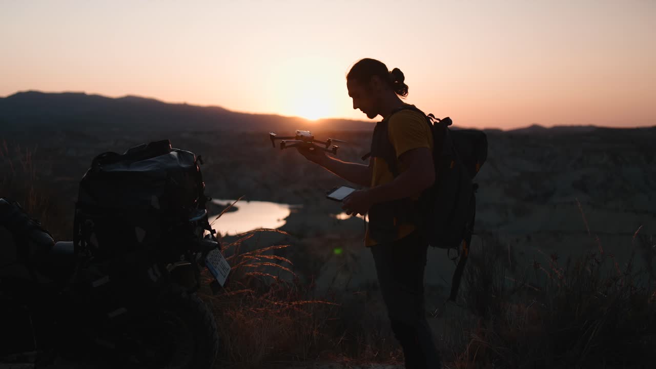 Silhouette of a backpacker with a motorcycle at sunset