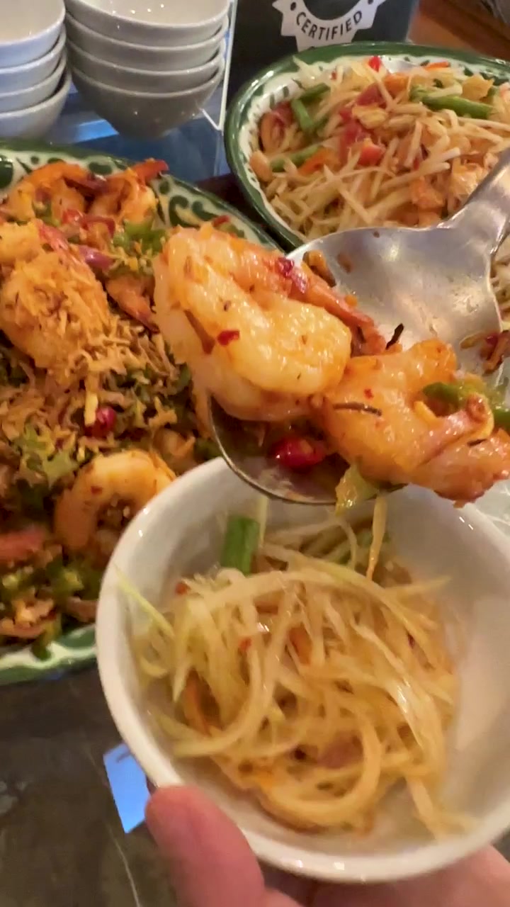 Sendok menyajikan salad udang pedas di atas salad pepaya dalam mangkuk putih kecil.