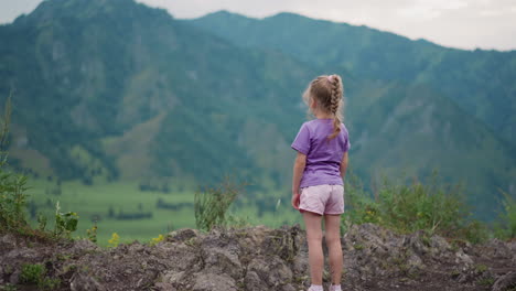 little girl with plait enjoys view of large mountains