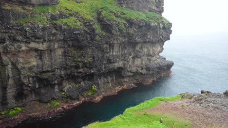 view of gjogv canyon's exit into the open atlantic ocean on a rainy day