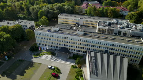 aerial wide angle orbit around sunny european university building among trees