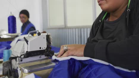 mixed race woman using sewing machine in factory