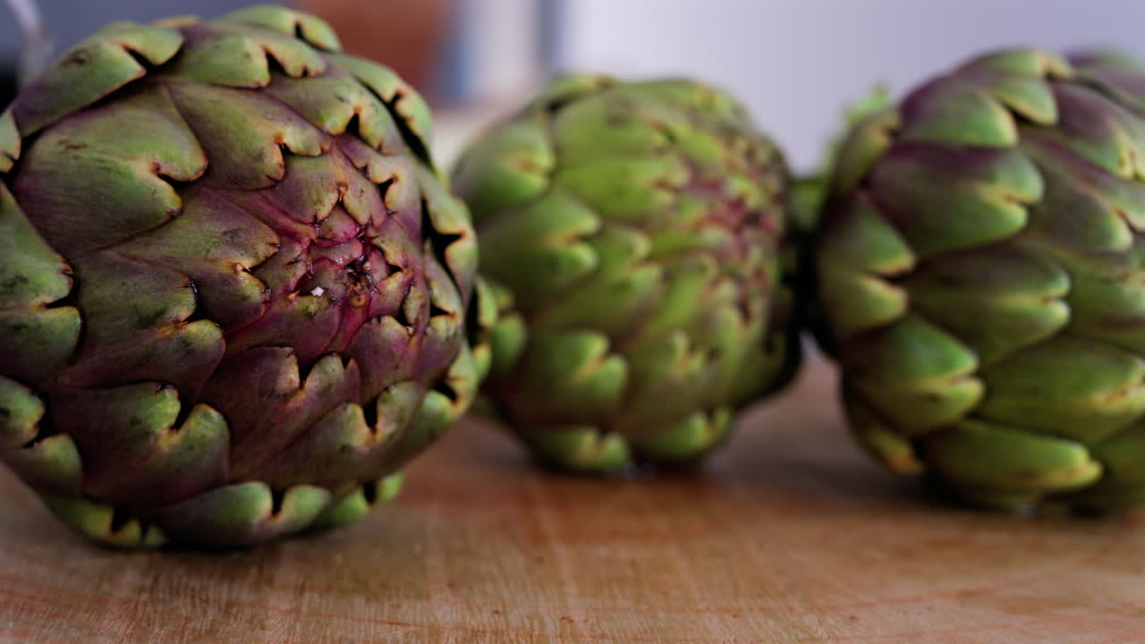 Close up of three artichokes on a wooden table