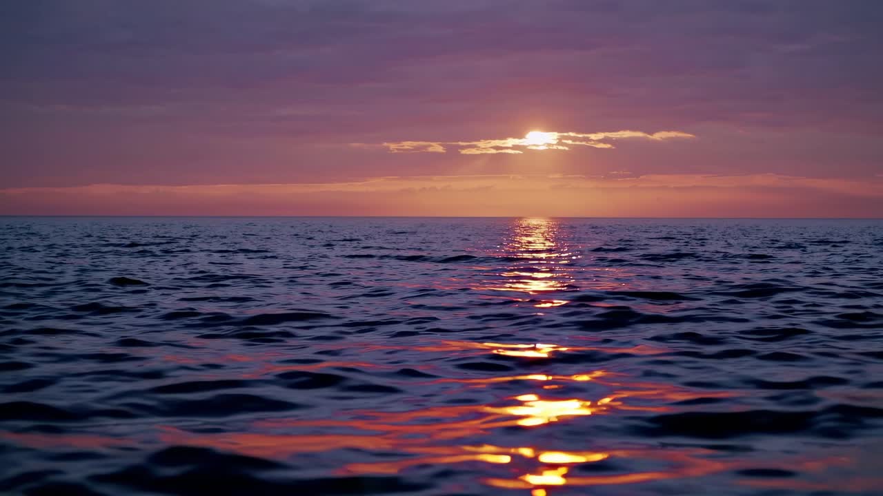 A serene sunset over the ocean with gentle waves, captured from a low-angle perspective