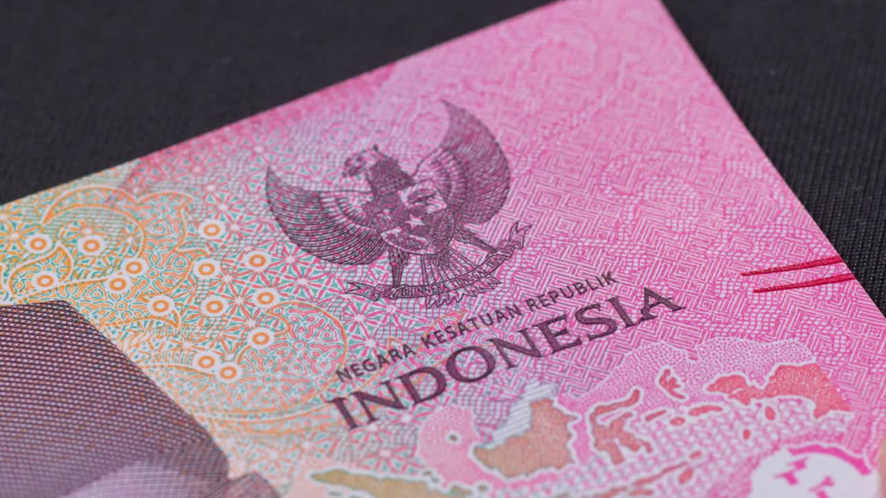 Macro shot of an Indonesian rupiah banknote showing intricate patterns, national emblem, and printed text. Currency detail highlights design, security, and cultural identity