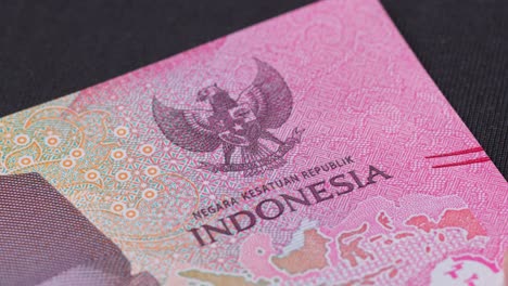 macro shot of an indonesian rupiah banknote showing intricate patterns, national emblem, and printed text. currency detail highlights design, security, and cultural identity