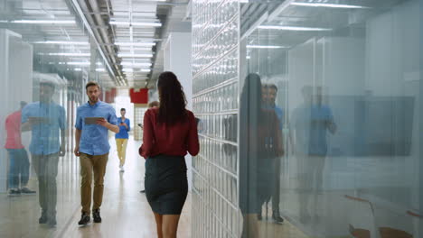 man rushing with tablet in modern office. people going on hallway indoors.